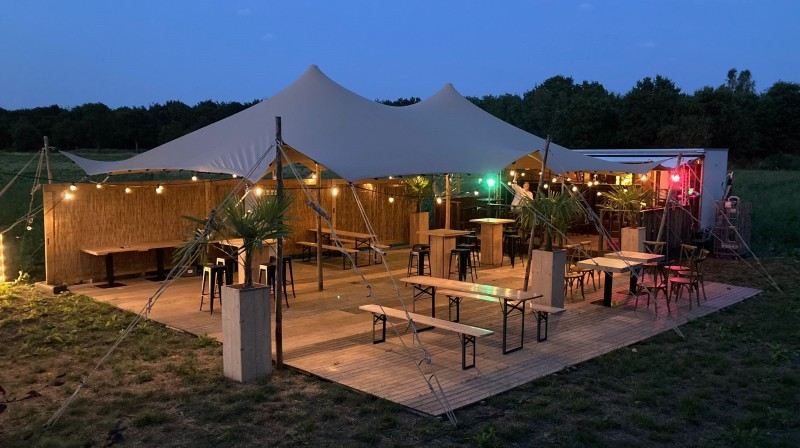 Stretchtent ingericht voor een feest met statafels, banken en verlichting
